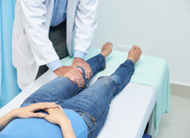 Cropped image of chiropractor checking knee of young patient